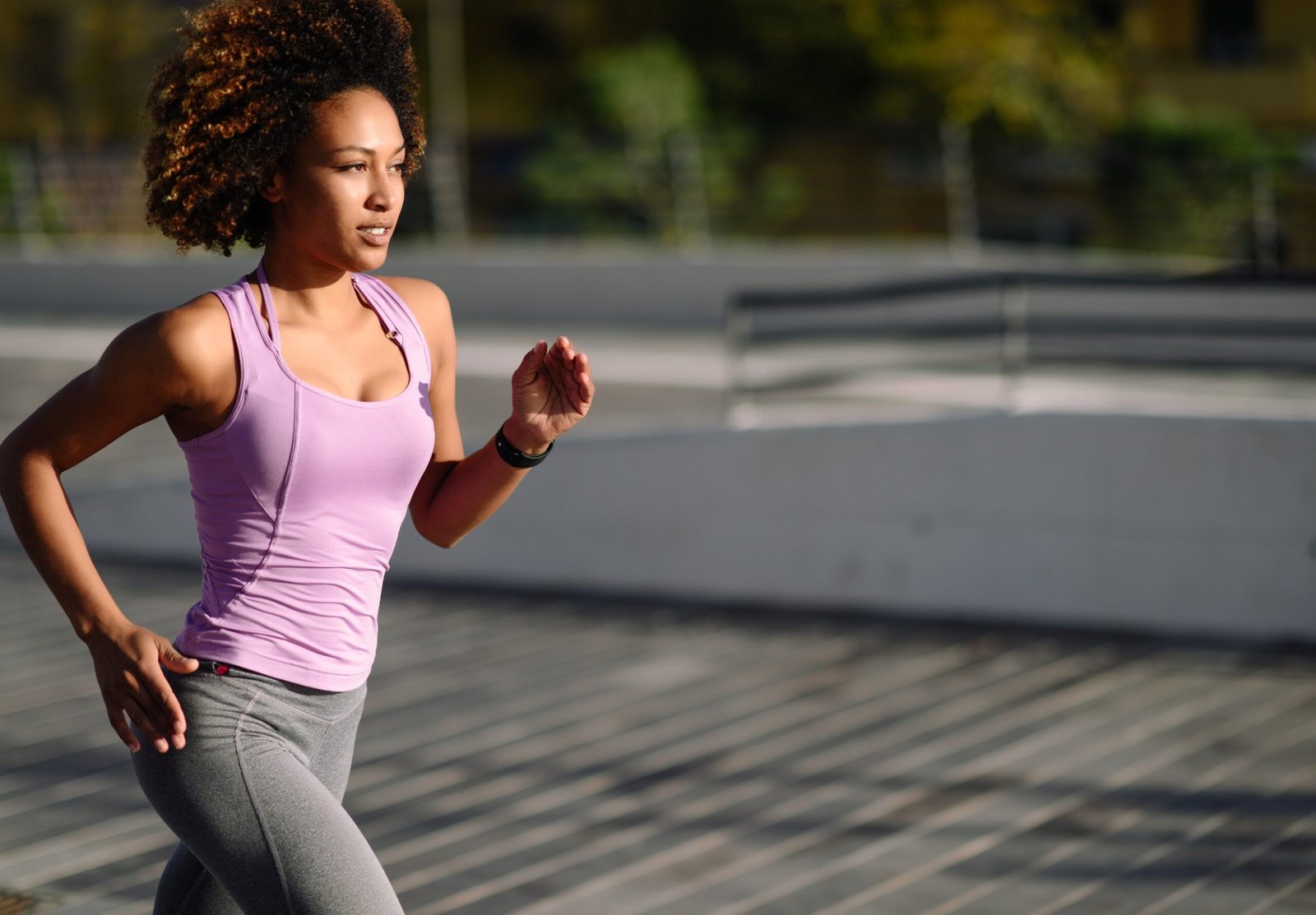Woman in pink tank top and grey leggings out for a jog.